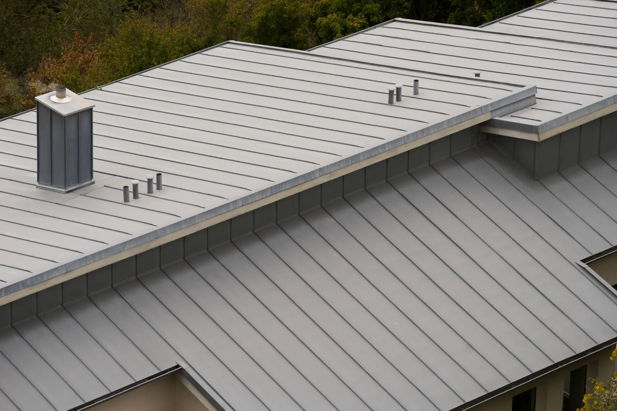 Low-slope metal roof on a modern building with multiple roof sections and vents.